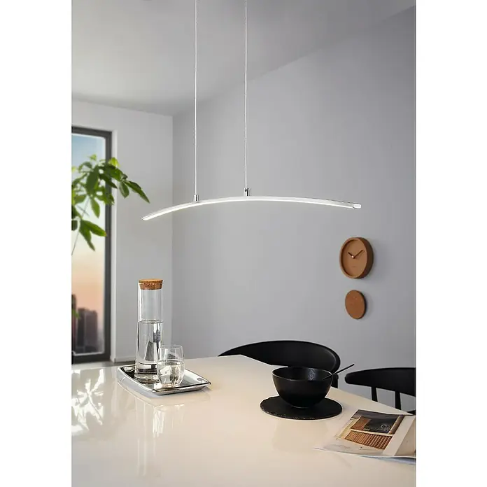 Eglo Style LED-Pendelleuchte Lasana - L x H: 90 x 100 cm - Hängeleuchte mit gebogener LED-Leiste über einem Esstisch, der mit einer Karaffe, einer Schale und Zeitschriften dekoriert ist.