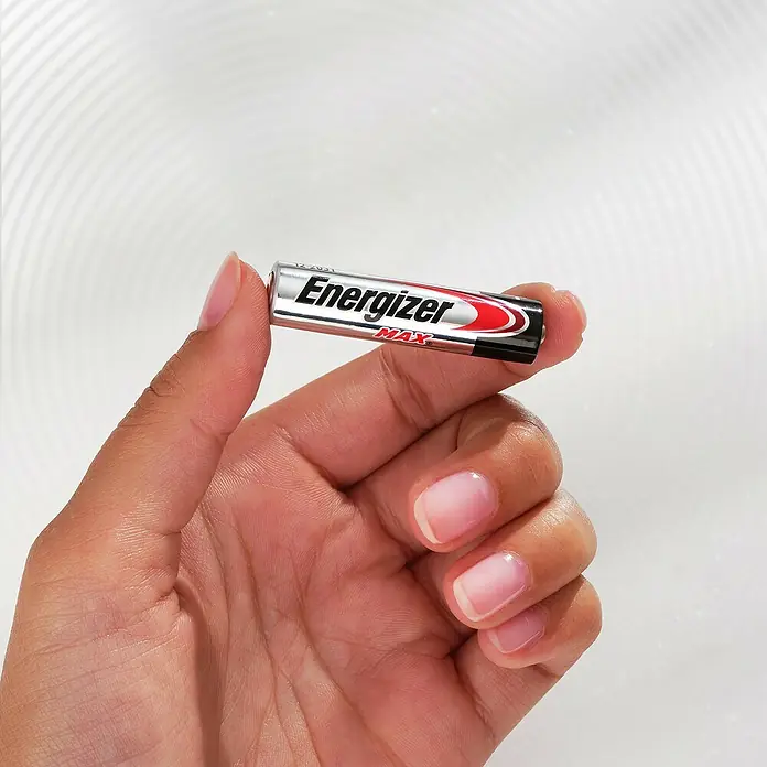Energizer Max Batterie - Micro AAA, 1,5 V, Alkali-Mangan, 20 Stk. - Nahaufnahme einer Hand, die eine Energizer Max AAA Batterie hält, silberfarben mit roten und schwarzen Akzenten, vor einem hellen Hintergrund.
