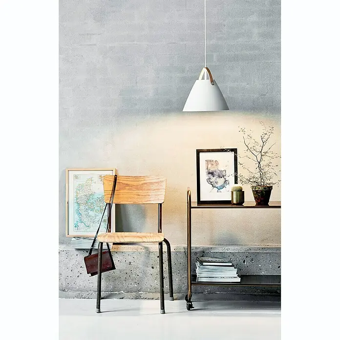 Nordlux Strap Lámpara colgante redonda - 60 W, Ø x Al: 27 x 27 cm, Blanco/Negro, E27 - Escena interior con una silla, una lámpara y una mesa pequeña con decoración, creando un ambiente acogedor con diseño artístico.