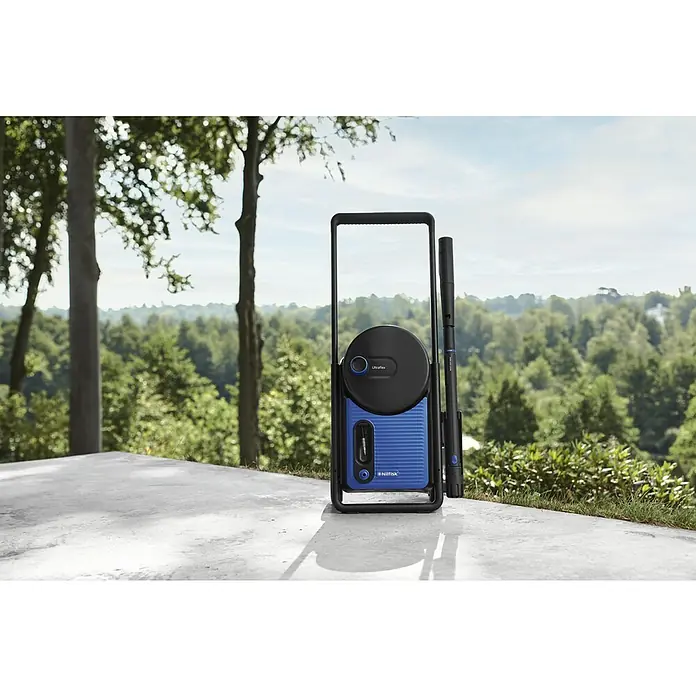 Nilfisk Hidrolimpiadora de alta presión Excellent 170 - 170 bar, 2.100 W, Capacidad de bombeo: 498 l/h - La imagen muestra una hidrolimpiadora Nilfisk en el exterior sobre un paisaje verde, destacando su construcción robusta y su diseño elegante.