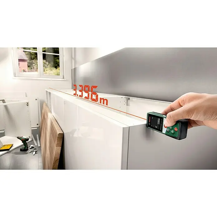 Bosch Universal Laserentfernungsmesser UniversalDistance 40 C - Messbereich: 0,05 - 40 m, Bluetooth 4.0 - Ein grünes Bosch Universal Distance Laser-Messgerät wird verwendet, um die Länge eines weißen Schrankes zu messen.
