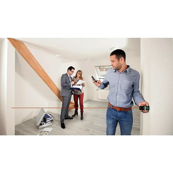 Bosch Universal Laserentfernungsmesser UniversalDistance 40 C - Messbereich: 0,05 - 40 m, Bluetooth 4.0 - Ein Mann benutzt einen Laser-Entfernungsmesser, um die Länge eines Raumes zu messen, während andere Personen im Hintergrund stehen.