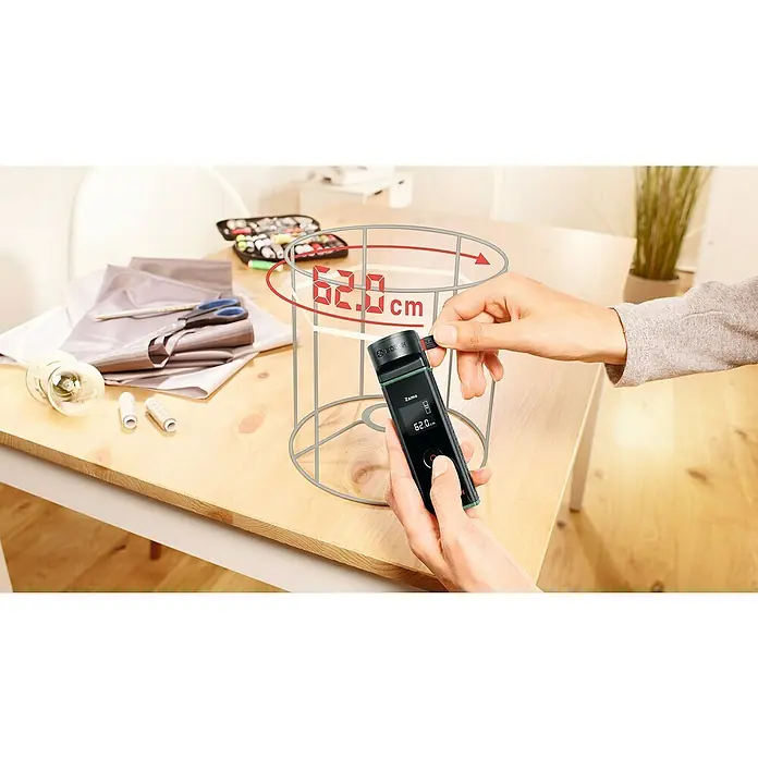 Bosch Bandmaß-Adapter Zamo - Passend für: Laser-Entfernungsmesser ZAMO IV - Eine Person misst mit einem Bosch Zamo 3 digitalem Laser-Entfernungsmesser den Durchmesser eines Lampenschirms mit 62 cm.