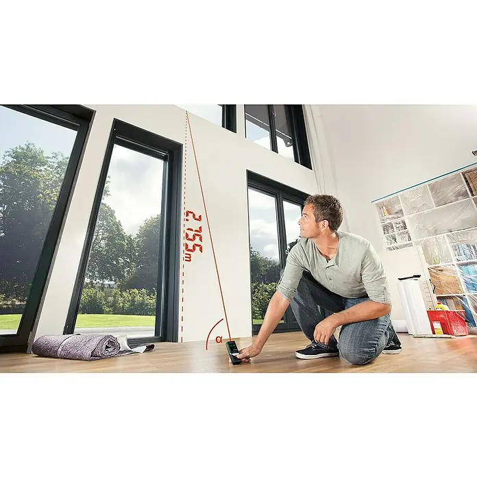 Bosch Advanced Laserentfernungsmesser AdvancedDistance 50 C - Messbereich: 0,05 - 50 m, Bluetooth 4.0 - Ein Mann misst mit einem Laser-Entfernungsmesser von Bosch einen Winkel und die Distanz in einem Raum mit großen Fenstern.