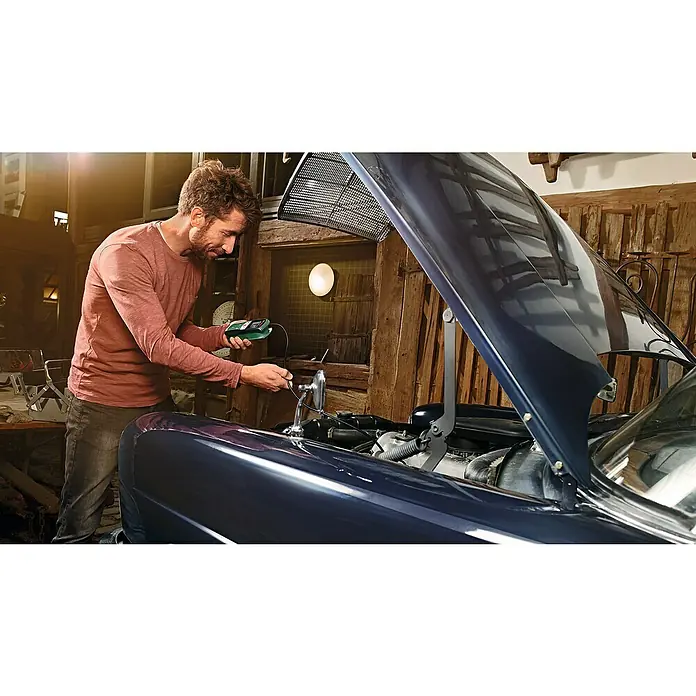 Bosch Universal Endoskopkamera UniversalInspect - Länge Schwanenhals: 95 cm, 11 -tlg. - Ein Mann benutzt ein Bosch-Diagnosegerät, um an einem Oldtimer zu arbeiten, wobei die Motorhaube geöffnet ist und die Details des Autos betont werden.