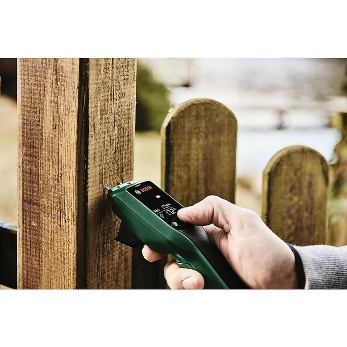 Bosch Universal Feuchtigkeitsmessgerät UniversalHumid - Geeignet für: Holz, Messbereich: 7,1 - 74,7 % - Nahaufnahme eines Bosch Universal Moisture Messgeräts bei der Messung der Holzfeuchtigkeit an einem Holzzaun.