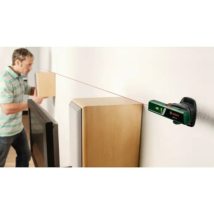 Bosch Easy Nivel láser Level - Número de niveles de burbuja: 2 ud. - Un nivel láser Bosch EasyLevel proyecta una línea roja en una pared, mientras un hombre está de pie en el fondo.