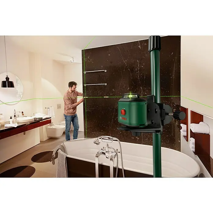 Bosch Teleskopstange TP 320 - Kunststoff, Arbeitshöhe: 10 cm - 320 cm - Ein Bosch Kreuzlinienlaser projiziert grüne Linien in einem Badezimmer, während ein Mann die Ausrichtung an einer Wand überprüft.