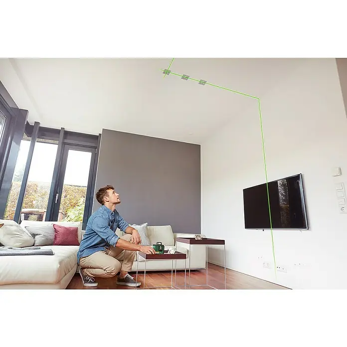 Bosch Kreuzlinienlaser AdvancedLevel 360Max. Arbeitsbereich: 12 m, 6 -tlg. - Mann mit Laser-Wasserwaage, die grüne Linien an Decke und Wand projiziert. Perfekt für präzise Ausrichtung bei Installationen.