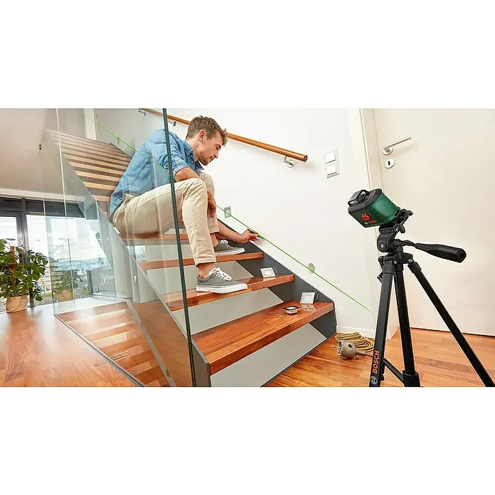Bosch Kreuzlinienlaser UniversalLevel 360 Set - Max. Arbeitsbereich: 12 m, 7 -tlg. - Ein Mann, der mit einem Bosch-Laser-Nivelliergerät auf einer Treppe arbeitet, um sicherzustellen, dass die Stufen eben sind.