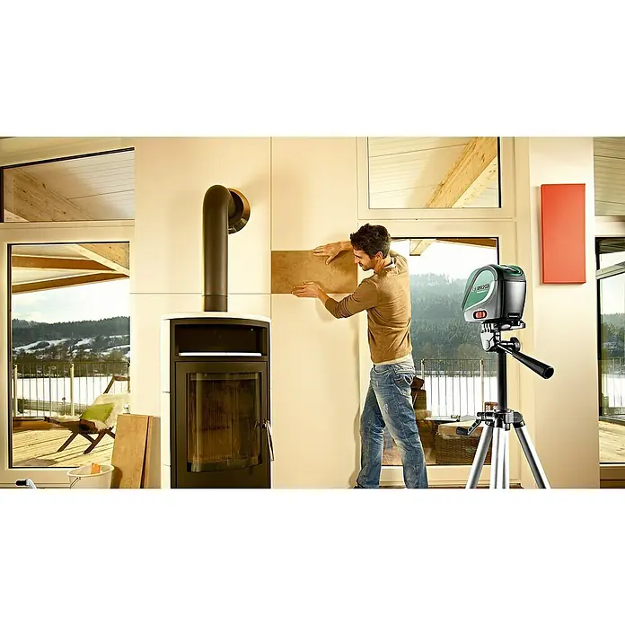 Bosch Kreuzlinienlaser UniversalLevel 2 - Max. Arbeitsbereich: 5 m - 20 m - Ein Mann verwendet einen Bosch Kreuzlinienlaser auf einem Stativ, um Fliesen an einer Wand neben einem Kamin anzubringen.