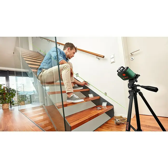 Bosch Stativ TT 150 - Höhenverstellung: 55 cm - 157 cm - Ein Mann nivelliert mit einem Bosch Kreuzlinienlaser eine Treppe, um LED Lampen einzubauen.