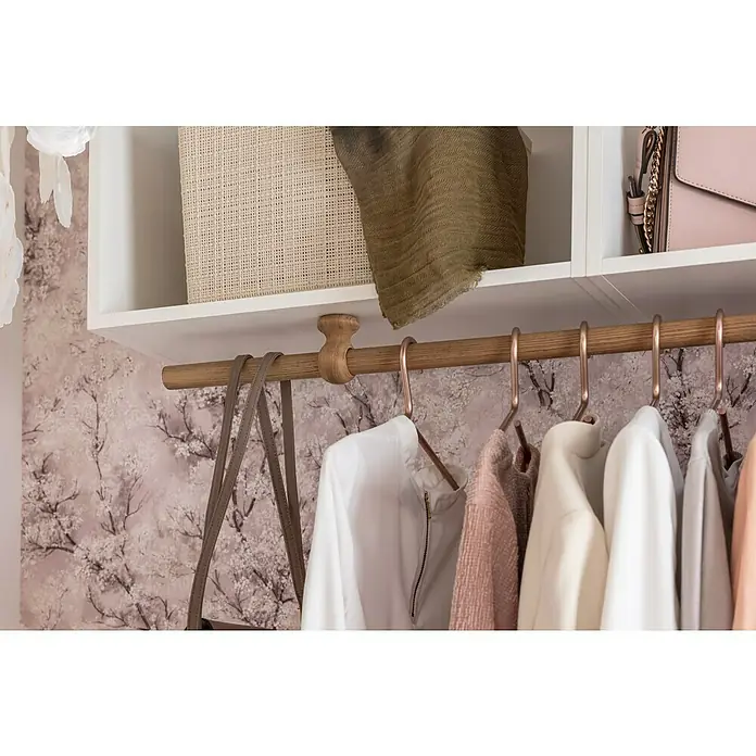 Expo Ambiente Deckenträger - Esche Gekälkt, Geeignet für: Gardinenstangen Ø 28 mm - Nahaufnahme eines Kleiderschranks mit einer Stange, an der Kleidung hängt, darüber Regale mit Körben und einer Handtasche.