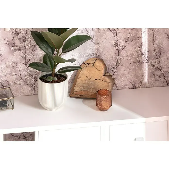 Piardino Gummibaum in SortenFicus elastica, Topfgröße: 24 cm - Ein Innenraum mit einem Ficus gummibaum in einem weißen Topf, einem Holzherz und einem bronzefarbenen Kerzenhalter auf einer weißen Oberfläche.