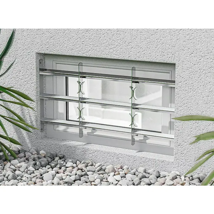 Stabilit Fenstergitter - Höhe: 450 mm, Auszugslänge: 70 cm - 105 cm, Fensterlaibungsmontage - Das Bild zeigt ein Kellerfenster mit einem Gitter aus verchromtem Stahl, das für Sicherheit und Schutz sorgt. Die Steine liegen im Vordergrund.