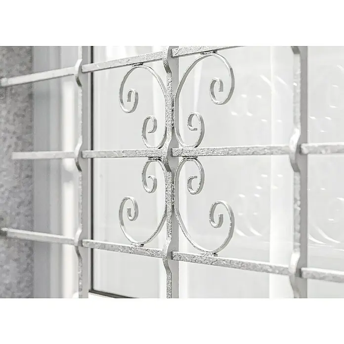 Fenstergitter Milo - B x H: 120 x 69 cm, Montage Fenstergitter: Fensterlaibungsmontage - Nahaufnahme eines kunstvoll gestalteten, silberfarbenen Fenstergitters, das Sicherheit mit dekorativer Eleganz verbindet.