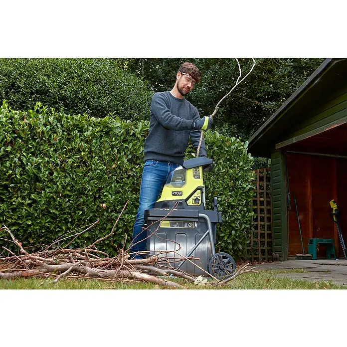 Ryobi Max Power Akku-Häcksler RY36SHX40-0 - Max. Aststärke: 4 cm - Ein Mann benutzt einen RYOBI Häcksler im Garten, um Äste zu zerkleinern, um Gartenabfälle zu reduzieren.