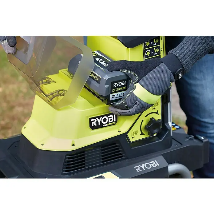 Ryobi Max Power Akku-Häcksler RY36SHX40-0 - Max. Aststärke: 4 cm - Ein RYOBI MAXPOWER Akku wird in ein gelbes RYOBI Gartengerät eingesetzt. Das Bild zeigt die sichere Verwendung mit Handschuhen.