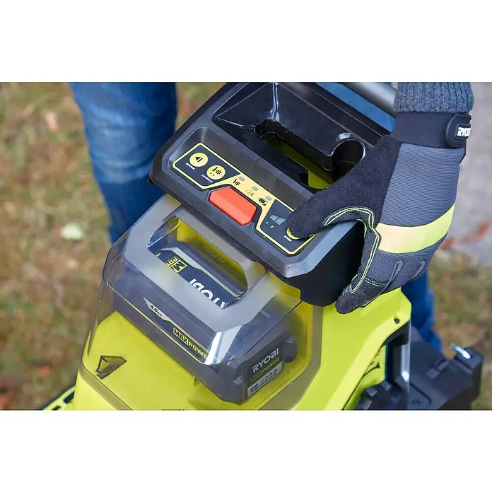 Ryobi Max Power Akku-Häcksler RY36SHX40-0 - Max. Aststärke: 4 cm - Nahaufnahme eines Akku-Gartengeräts von Ryobi, bei dem eine Hand die Geschwindigkeitsregelung bedient. Fokus auf dem grünen Gerät und der Bedienung.