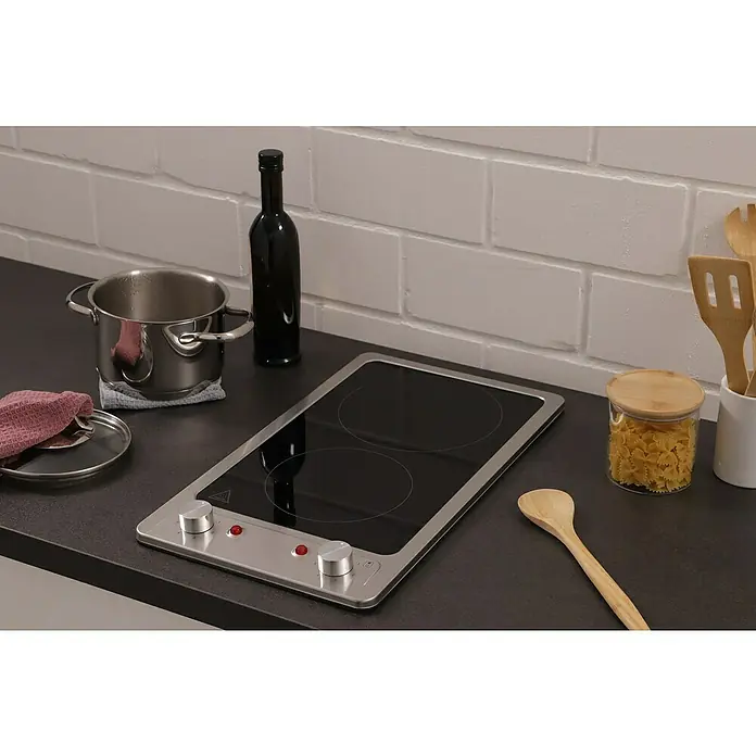 Respekta Kochfeld Vinzenz - Glas, Anzahl Normalkochstellen: 2 Stk. - Das Bild zeigt einen modernen Induktionsherd mit zwei Kochfeldern, umgeben von Kochutensilien wie Topf, Nudeln und Holzlöffeln.