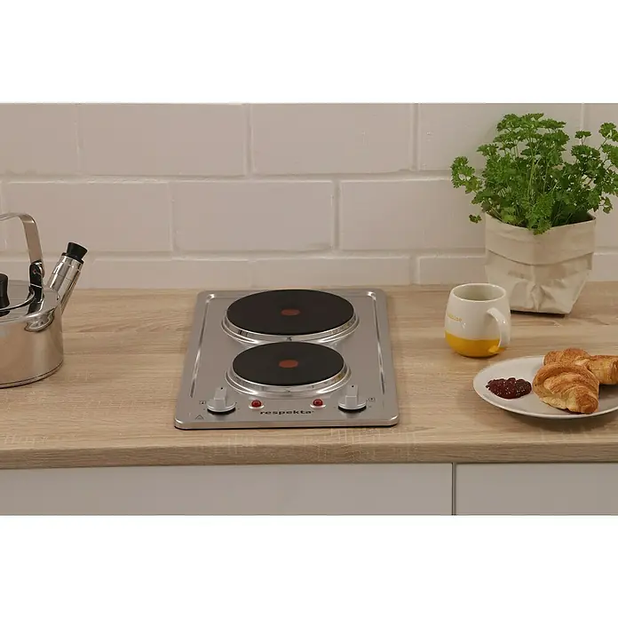 Respekta Kochfeld Zeno - Edelstahl, Anzahl Normalkochstellen: 2 Stk. - Das Respekta Kochfeld, eine kompakte Kochlösung, ist elegant auf einer Küchentheke mit Wasserkocher, Tasse und Gebäck platziert.