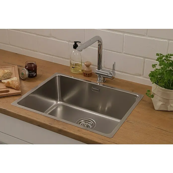 Respekta Einbauspüle Detroit - 58,8 x 43,5 cm, Edelstahl - Spültisch aus Edelstahl mit Armatur, Seifenspender, Holzbürste, Kräutertopf, Brot und Marmelade auf einer Arbeitsplatte.