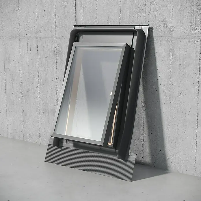 Salida de techo Fenstro - 45 x 73 cm, Color exterior: RAL 7043 - Una claraboya moderna con un marco delgado se apoya contra una pared de hormigón, ofreciendo una solución de iluminación elegante para cualquier hogar.