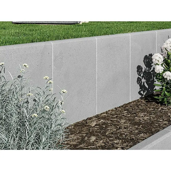 Diephaus L-Stein - 50 cm, 40 cm, Stärke: 7 cm, Grau - Ein gepflegter Garten mit grauer Betonmauer, bepflanzt mit weißen Blüten und Mulch, der eine moderne und stilvolle Gartengestaltung zeigt.