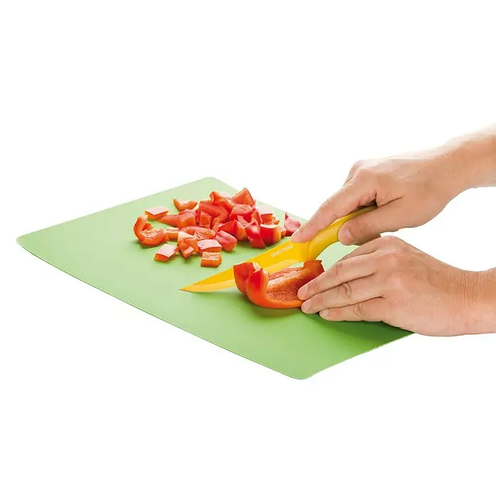 Tescoma Schneidebrett-Set PrestoKunststoff, 3 Stk. - Ein gelbes Tescoma-Messer schneidet Paprika auf einem grünen Schneidebrett.