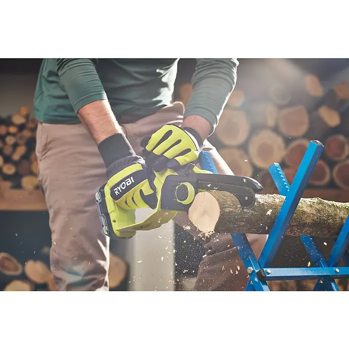 Ryobi ONE+HP Akku-Astsäge RY18PSX15A-120T - 18 V, 2 Ah, Li-Ionen, 1 Akku, Schwertlänge: 15 cm - Ein Mann sägt Holz mit einer RYOBI Akku-Kettensäge, die durch einen blauen Sägebock gehalten wird. Holzscheite sind im Hintergrund gestapelt.