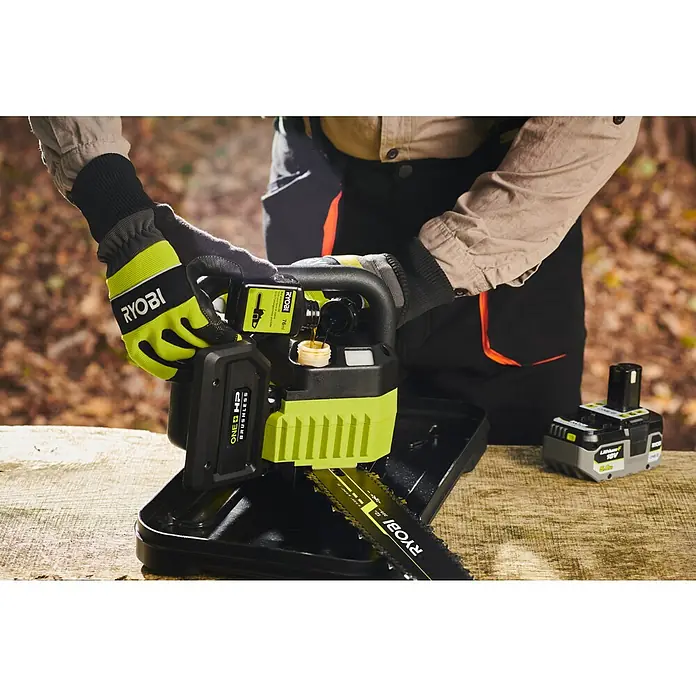 Ryobi ONE+HP Akku-Kettensäge RY18CSX30A-0 - 18 V, Li-Ionen, Ohne Akku, Schwertlänge: 30 cm - Eine Person füllt Öl in eine Ryobi Astsäge, die auf einem Holztisch steht.