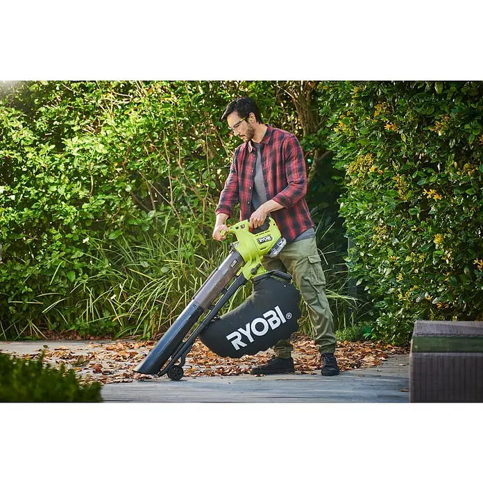 Ryobi ONE+HP Akku-Laubsauger & -Laubbläser RY18BVXA-0 - Ohne Akku, Blasleistung: 1,8 m³/min, Blasgeschwindigkeit: 252 m/s - Ein Mann benutzt einen Ryobi Laubbläser/Sauger im Garten, um Laub zu entfernen. Das Gerät ist grün und schwarz und hat einen großen Fangsack.