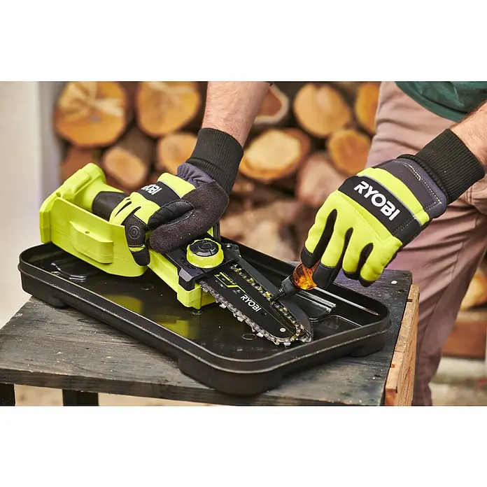 Ryobi ONE+HP Akku-Astsäge RY18PSX15A-0 - 18 V, Li-Ionen, Ohne Akku, Schwertlänge: 15 cm - Ein gelb-schwarzer Ryobi Akku-Kettensäge wird mit Öl geschmiert. Ryobi Handschuhe sind zu sehen.