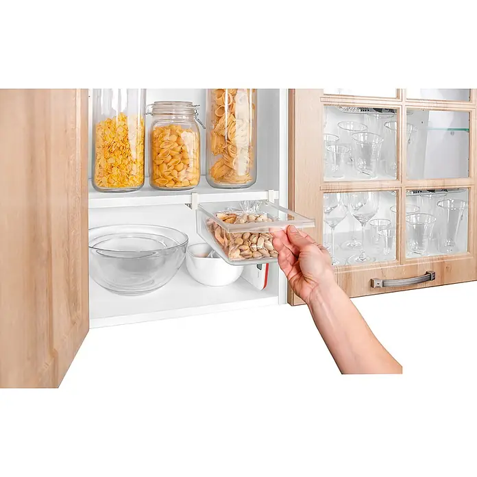Tescoma Schublade Flexi Space - 19 x 29 cm - Ein Küchenschrank mit durchsichtigen Behältern mit verschiedenen Lebensmitteln und einem transparenten Schubfach mit Pistazien, das von einer Hand herausgezogen wird.