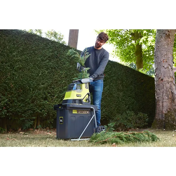 Ryobi Max Power Akku-Häcksler RY36SHX40-0 - Max. Aststärke: 4 cm - Mann benutzt einen Ryobi-Häcksler im Garten. Der Häcksler ist gelb, schwarz und grau und hat einen Behälter für die gehäckselten Äste.