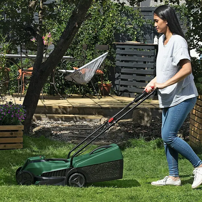 Bosch Power for All 18V Akku-Rasenmäher EasyMower 18V-32-150 - 18 V, 1 Akku, 3 Ah, Schnittbreite: 32 cm - Frau mit einem grünen Rasenmäher im Garten. Der Rasenmäher ist das Hauptprodukt im Bild.