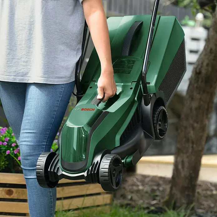 Bosch Power for All 18V Akku-Rasenmäher EasyMower 18V-32-150 - 18 V, 1 Akku, 3 Ah, Schnittbreite: 32 cm - Eine Person trägt einen grünen Bosch Rasenmäher. Der Rasenmäher ist leicht und kompakt, ideal für kleine Gärten.