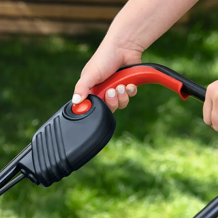 Bosch Power for All 18V Akku-Rasenmäher EasyMower 18V-32-150 - 18 V, 1 Akku, 3 Ah, Schnittbreite: 32 cm - Eine Hand bedient den roten Startknopf eines Rasenmähers mit schwarzem Griff. Der Rasenmäher ist bereit für den Einsatz im Garten.