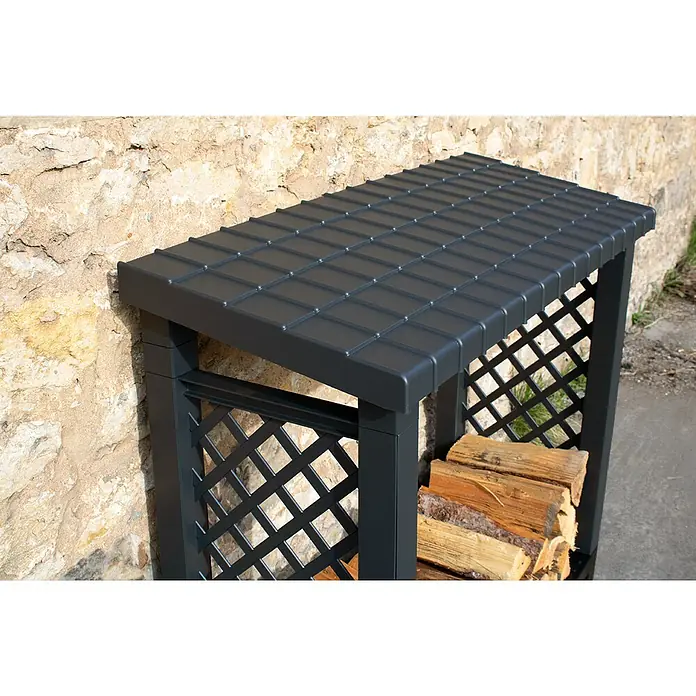 KHW Kaminholzregal - 114 x 47 x 102 cm, Kunststoff, Anthrazit - Ein graues Holzregal mit Lattenrostseiten und einem Dach, das an einer Wand steht und Brennholz enthält.