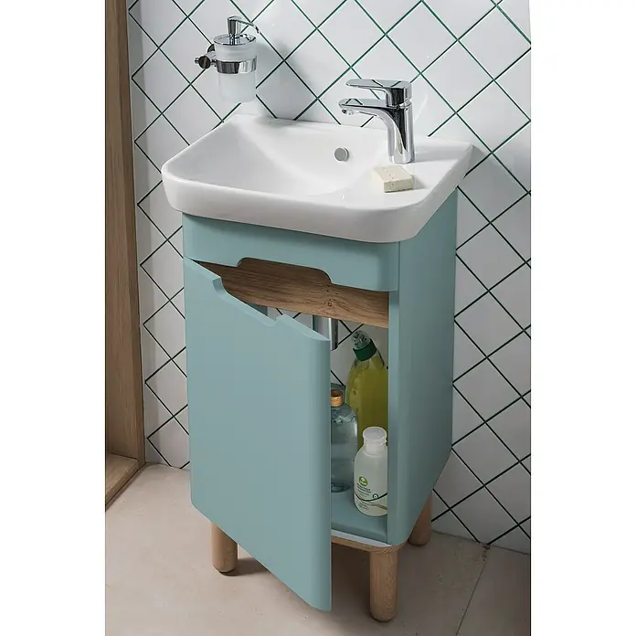 VitrA Sento Badmöbel-Set - Gesamtbreite Badmöbel: 50 cm, Fjordgrün, Matt, DIN Anschlag: Links - Bild eines Waschbeckens mit Unterschrank in einem Badezimmer. Der hellblaue Schrank hat eine offene Tür, die den Blick auf Reinigungsmittel freigibt.