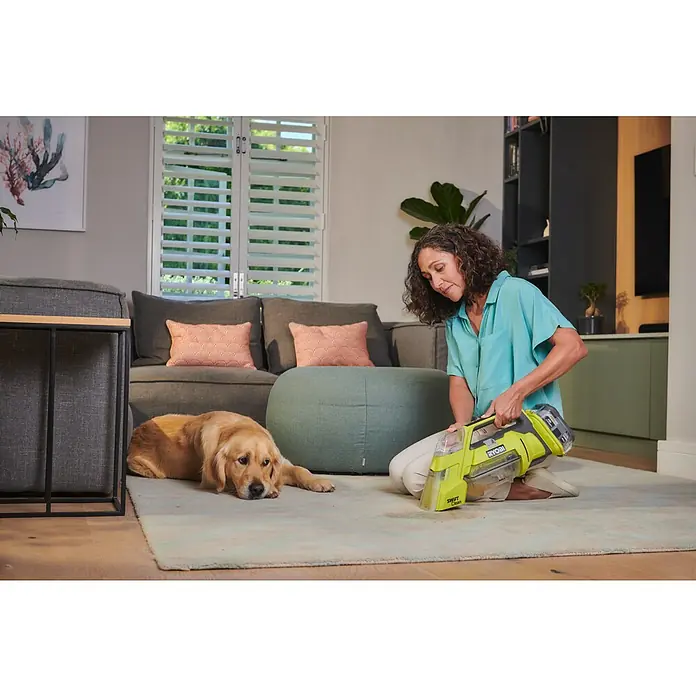 Ryobi ONE+ Akku-Nass-Trockensauger RDC18-0 - 18 V, Ohne Akku, Behältervolumen: 200 l - Frau reinigt mit dem Ryobi Swift Clean Teppichreiniger einen Teppich, während ein Golden Retriever daneben liegt.