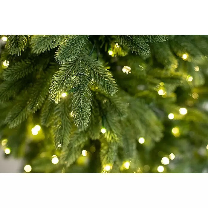 Künstlicher Weihnachtsbaum Roswell - Höhe: 150 cm, Grün, LED-Beleuchtung - Nahaufnahme grüner Tannenbaumzweige mit warmweißen LED-Lichtern geschmückt.