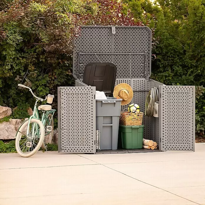 Lifetime Mülltonnenbox Phil - Kunststoff, Grau/Braun, Geeignet für Anzahl Mülltonnen: 2 Stk. - Großer grauer Outdoor-Geräteschuppen, offen, gefüllt mit Behältern, Gartenschlauch, Holzscheiten und einem Hut. Ein türkises Fahrrad lehnt daneben.
