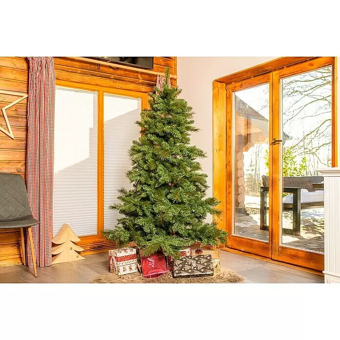 Künstlicher Weihnachtsbaum Mesa - Höhe: 180 cm, Grün, Standfuß - Ein grüner künstlicher Weihnachtsbaum steht drinnen, umgeben von verpackten Geschenken auf einem Teppich.