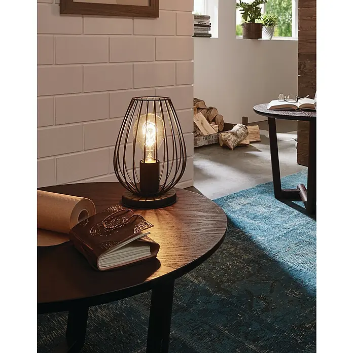 Eglo Newtown Tischleuchte rund - 60 W, Ø x H: 160 mm x 23 cm, Schwarz, E27 - Nahaufnahme einer Retro-Tischlampe mit Käfigdesign auf einem Beistelltisch, die ein warmes, einladendes Licht ausstrahlt.