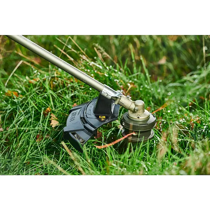 Ryobi ONE+HP Akku-Freischneider RY18BCX26A-0 - 18 V, Ohne Akku, Schnittbreite Faden: 38 cm, Schnittbreite Messer: 26 cm - Nahaufnahme eines Ryobi Rasentrimmers im grünen Gras, bereit für den Einsatz im Garten.