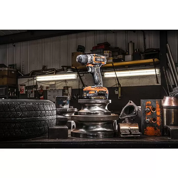AEG Pro 18V Taladro atornillador de batería BS18SBL-202C - 18 V, 2 baterías, 2 Ah, 60 Nm - Taladro atornillador inalámbrico AEG naranja y negro sobre herramientas metálicas en un taller industrial.