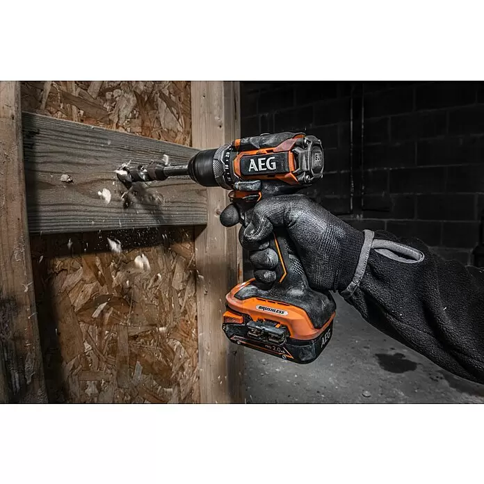 AEG Pro 18V Taladro atornillador de batería BS18SBL-202C - 18 V, 2 baterías, 2 Ah, 60 Nm - Taladro inalámbrico AEG naranja y negro, sostenido por mano enguantada, perforando viga de madera con virutas volando.