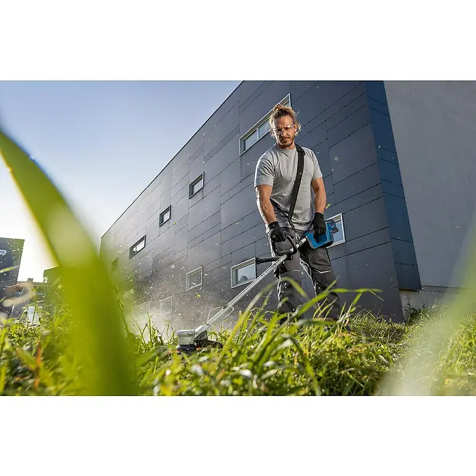 Bosch Professional AMPShare 18V Akku-Rasentrimmer GRT 18V-33 - 18 V, Ohne Akku - Ein Mann benutzt einen Rasentrimmer, um das Gras vor einem Gebäude zu schneiden. Das Gerät ist kabellos und verfügt über einen Akku.