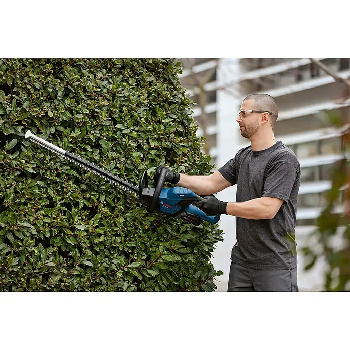 Bosch Professional AMPShare 18V Akku-Heckenschere GHE 18V-50 - 18 V, Ohne Akku, Schnittlänge: 50 cm - Ein Mann schneidet eine Hecke mit einer Bosch Akku-Heckenschere, wobei das Produkt und seine Verwendung hervorgehoben werden.